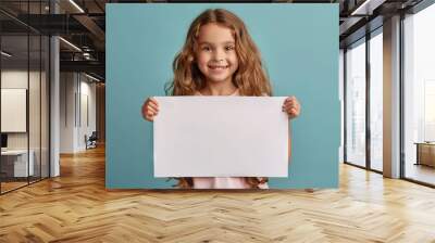 a happy young girl hold a blank sign on pastel blue background Wall mural