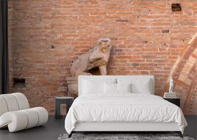 Architectural detail featuring a stone lion sculpture on a brick wall in Bologna. The sculpture sits on a base, adding a decorative aspect to the building exterior Wall mural