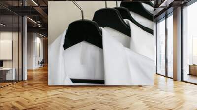 Closeup of white shirts hanging in row on the rail of clothes rack on white background Wall mural