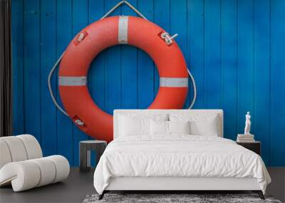 The orange lifebuoy ring hangs on a bright blue wooden wall Wall mural