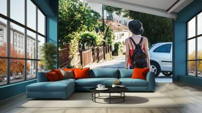 Girl in a black hat walking down the street in summer Wall mural