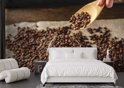 Hand pouring fragrant coffee beans into a burlap. Pile of roasted Arabica grains. Selection of fresh coffee for espresso Wall mural