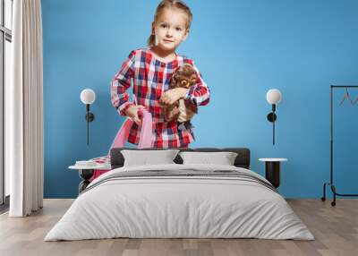 Little girl with a suitcase and a favorite toy on a blue background. Travel concept Wall mural