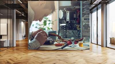 Man repairman is trying to fix using the tools on the computer that is on a workplace in the office Wall mural