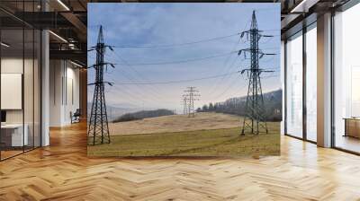 Old power grid transmission towers on agricultural land and pastures in a national park.  Rusty high-voltage electricity pylons under blue sky in grassland highlands. Litomerice, Czechia, Europe. Wall mural