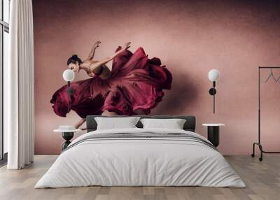 Graceful woman dancing in flowing dark red dress Wall mural