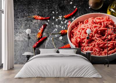 Minced meat in a bowl on a table with chili pepper pods.  Wall mural