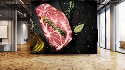 Raw pork steak with a sprig of rosemary on a stone board.  Wall mural