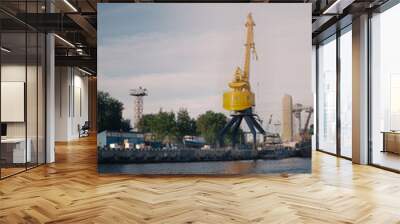 An industrial crane stands by the water in a vibrant urban setting, showcasing development Wall mural