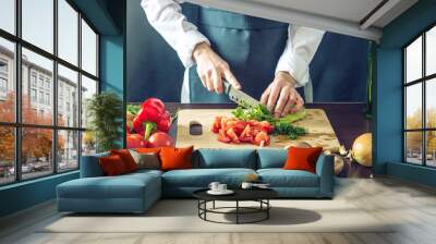 The chef in black apron cuts vegetables. Concept of eco-friendly products for cooking Wall mural