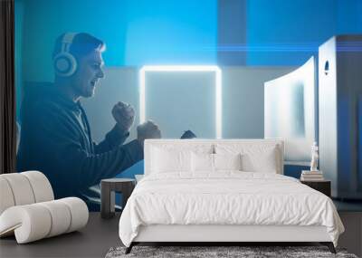 The gamer with headphones playing video games on the illuminated background Wall mural