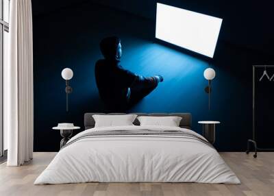 The man sitting in the dark room in front of a white screen Wall mural