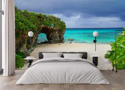 Travel to famous Paradise beach of Sunayama on Miyako Island in Japan. Seascape against blue stormy sky before rain, bright birch water, snow-white sand and a stone cliff overgrown with greenery  Wall mural