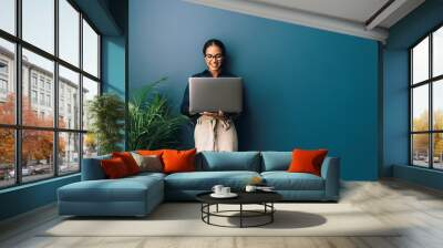 Beautiful businesswoman standing at home and holding laptop computer oh hands Wall mural