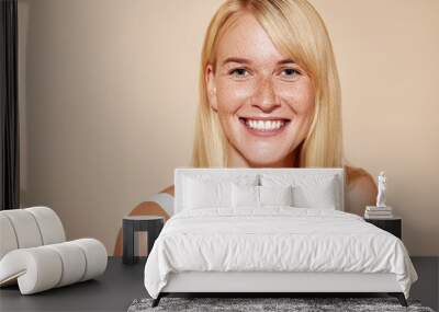 Cheerful blond female with perfect smooth skin looking at camera. Portrait of a happy freckled woman looking straight at a camera. Wall mural