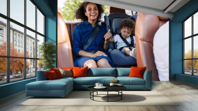 Happy mother and her son sitting on a backseat while traveling in a car Wall mural