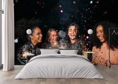 Happy women at night. Laughing friends with sparklers under confetti. Wall mural