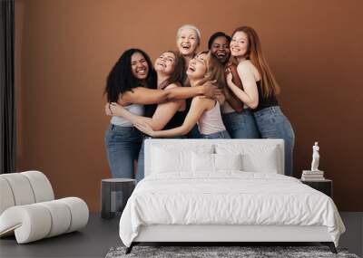 Six laughing women of a different race, age, and figure type. Group of multiracial females having fun against a brown background. Wall mural