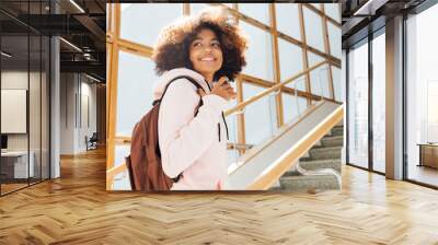 Smiling girl looking back while standing on stairs in school. Student going for the lecture. Wall mural