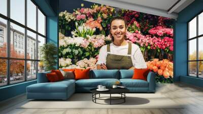 Woman florist standing in flower shop. Female florist in apron standing with her arms crossed. Wall mural