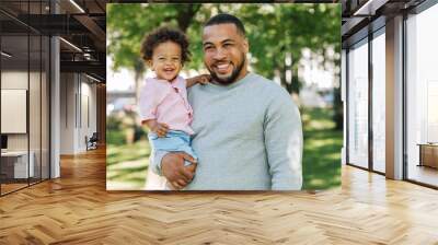 Young father holding son on hands. Happy little boy and his father in the park. Wall mural