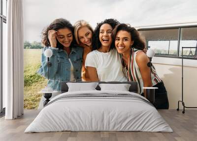 Young laughing women standing at van having good times during summer vacation Wall mural