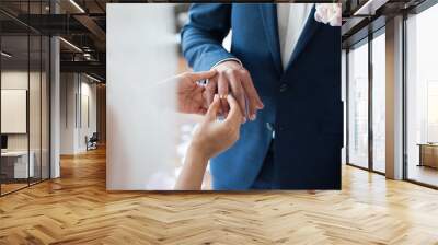 Bride puts ring on groom's finger Wall mural