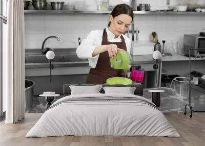 Female pastry chef decorates a mousse cake with a mirror glaze. Wall mural