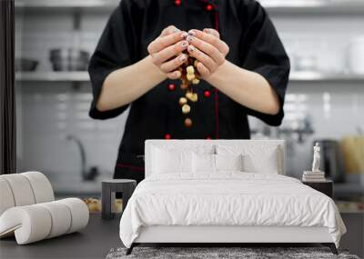 Pastry chef pours a lot of hazelnuts into a bowl for making pralines. Wall mural