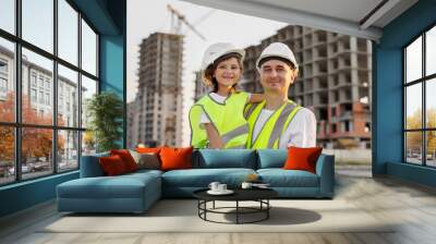 Portrait of a father and daughter in protective helmets on the background of a construction site. Wall mural