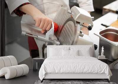 The chef in the restaurant kitchen prepares tomato slices with a slicer. Wall mural