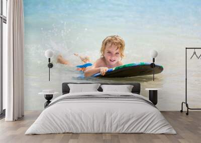 Young surfer, happy young boy in the ocean on surfboard Wall mural