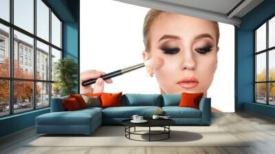 Makeup artist applies blush and powder on the face of the client woman with a brush Wall mural