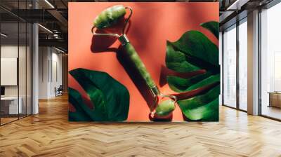 Jade roller with monstera leaves on sunny surface with shadows Wall mural