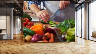 Chef slicing cucumber with a knife on chopping board Wall mural