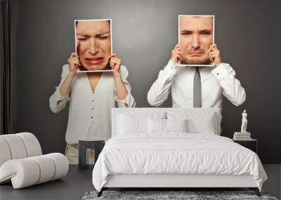 man and woman holding frames with sad faces Wall mural