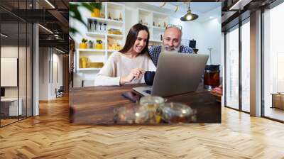 side view of smiling couple looking at the screen of a laptop at Wall mural