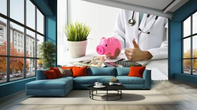 Medical and health insurance concept, Doctor holding piggy bank and money in hospital background, Money saving for medical care expenses. Wall mural