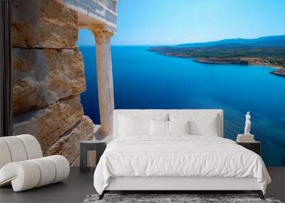 An ancient temple with classic columns stands dramatically on a cliff overlooking a stunningly blue sea. Wall mural