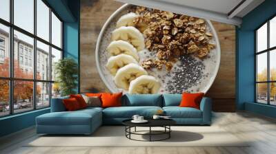 A healthy smoothie bowl topped with granola, banana slices, and chia seeds, presented on a wooden table. Wall mural