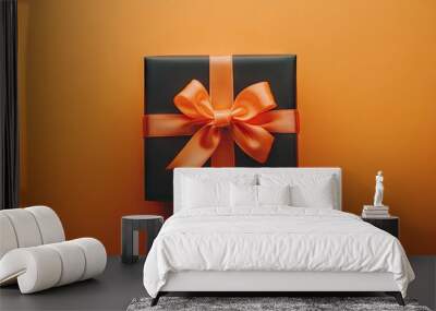 Elegant Black Gift Box with Orange Ribbon on Vibrant Background Wall mural