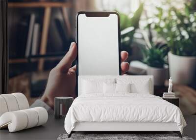 Man using a smartphone with a blank white screen at home office desk, space for mockup purposes. - Wall mural