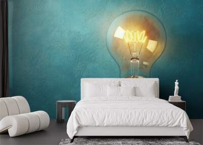 Top view of a light bulb on a bright surface with a large open area beside it for copy or branding. Wall mural