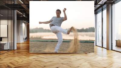 Athletic capoeira performer workout training on the beach sunris Wall mural