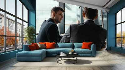 Focused businessman listening to business partner talking during discussion, thinking over his ideas while sitting at the table Wall mural