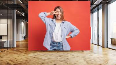 Funny, carefree girl having fun isolated on a red background with open mouth Wall mural