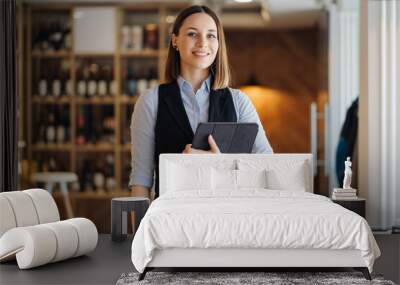 Image of beautiful young woman standing while holding a digital tablet in her hands. Business owner, cafeteria, restaurant Wall mural