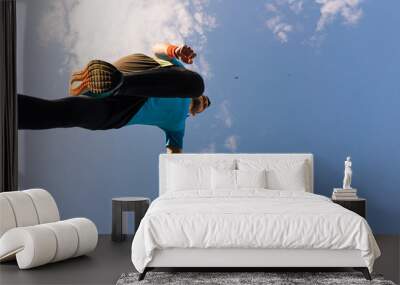 Low angle view of a sportsman who jump and run with blue sky in background Wall mural