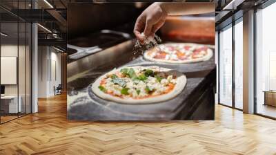 Pizza making process. Male chef hands making authentic pizza in the pizzeria kitchen. Wall mural