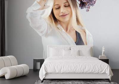 Portrait of a beautiful young girl in white shirt, black top and shorts, holding a big bouquet of dried flowers over gray background splashed by lines of light Wall mural